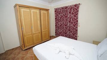 A bedroom with a bed, a wardrobe, and a red patterned curtain.