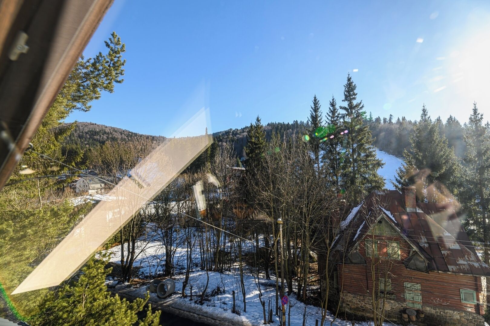 Un paysage enneigé avec des maisons, des arbres et un ciel dégagé.