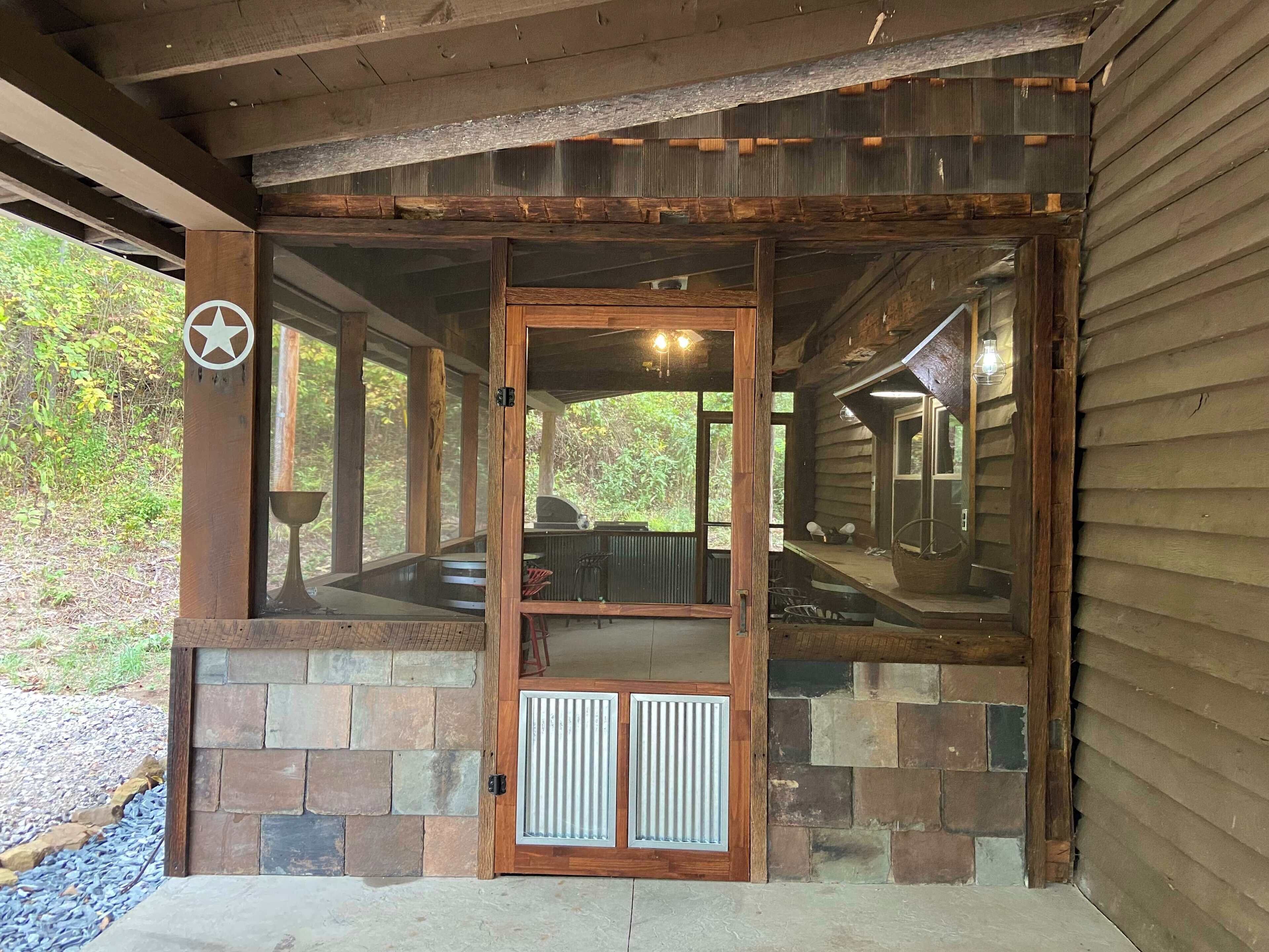 A wooden cabin with a stone foundation, a glass door, and a star logo on the door frame.