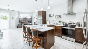 A modern kitchen with a central island, stainless steel appliances, and pendant lighting. - Family Fun Beach Townhome w/ Pool, BBQ & Game Room! 🌊🏖️ (Indian Harbour Beach)