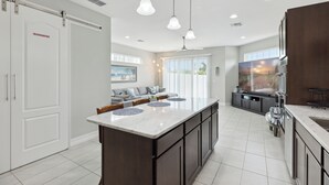 A modern kitchen with a large island, dark cabinetry, and pendant lighting. - Family Fun Beach Townhome w/ Pool, BBQ & Game Room! 🌊🏖️ (Indian Harbour Beach)