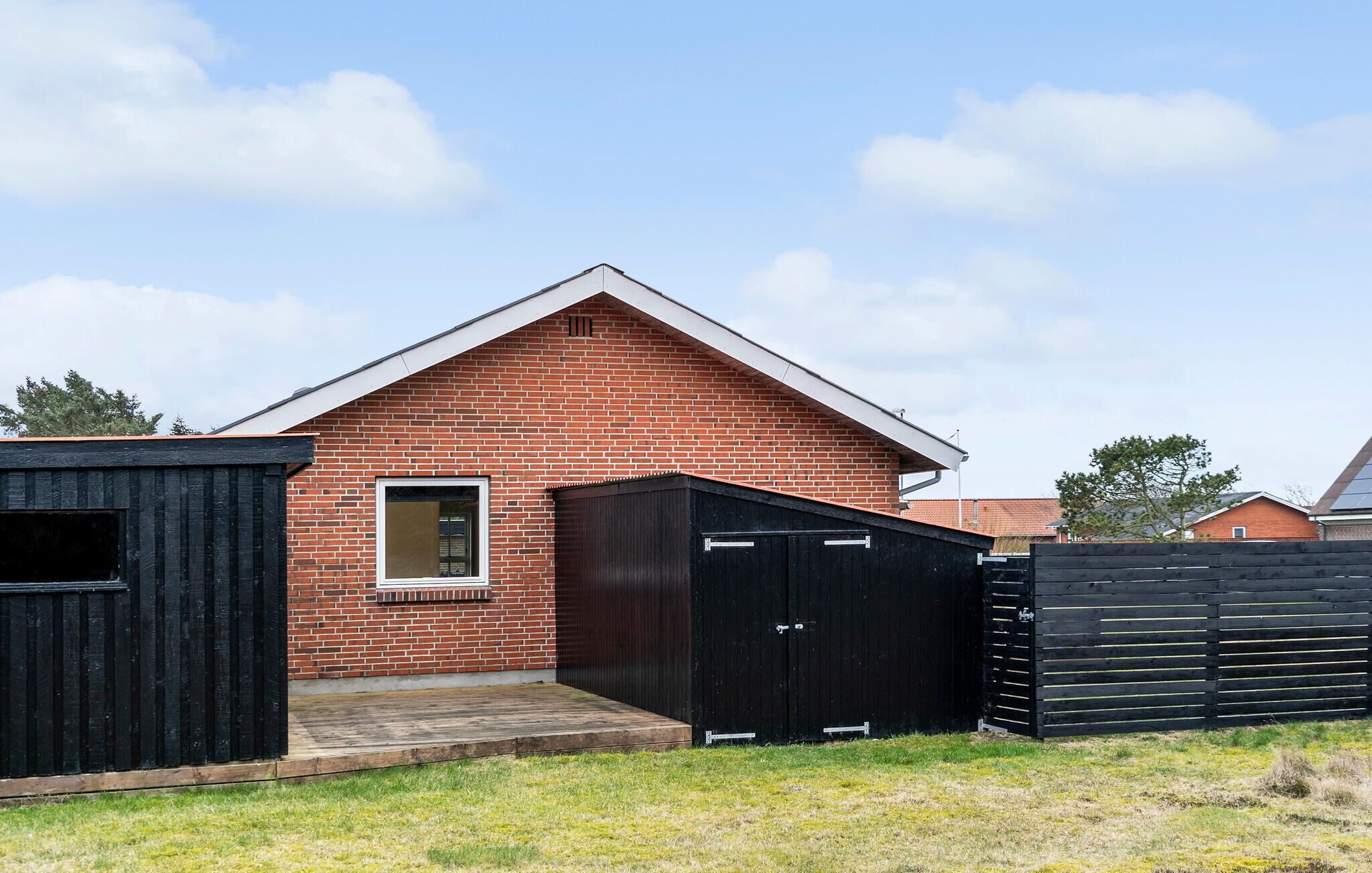 A brick building with a triangular roof, a window, and a black door.