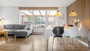 A modern living room with a grey sofa, wooden flooring, and a dining area with a table and chairs. - Amazing home in Vestervig with WiFi (Vestervig)
