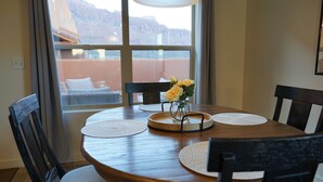 En spiseplads med et træbord, fire stole og en vase med gule blomster.