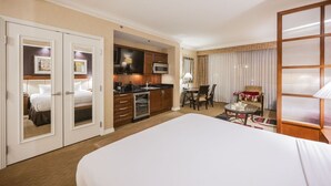 Une chambre d’hôtel dotée d’un grand lit, d’une kitchenette, d’un coin repas et d’une salle de bain séparée.
