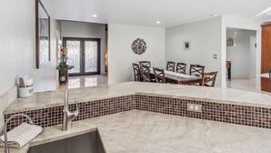 Una cucina moderna con un piano di lavoro in marmo, uno schienale piastrellato e un'area pranzo con tavolo e sedie.
