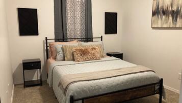Une chambre à coucher comprenant un lit, deux tables de chevet, une tête de lit, une fenêtre avec des rideaux et deux haut-parleurs fixés au mur.