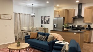 A modern living room with a blue sofa, a wooden coffee table, and a patterned rug.