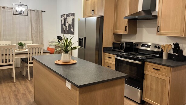 A modern kitchen with wooden cabinets, stainless steel appliances, and a central island.