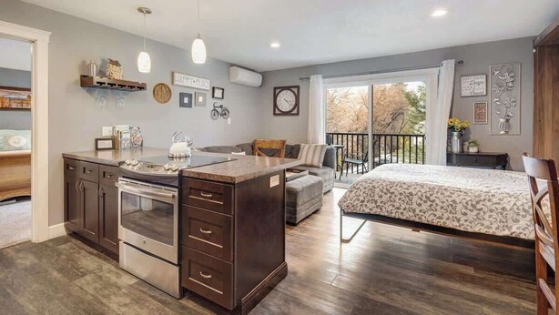 Une chambre spacieuse avec un grand lit, un coin salon séparé et une cuisine équipée d’une cuisinière intégrée.