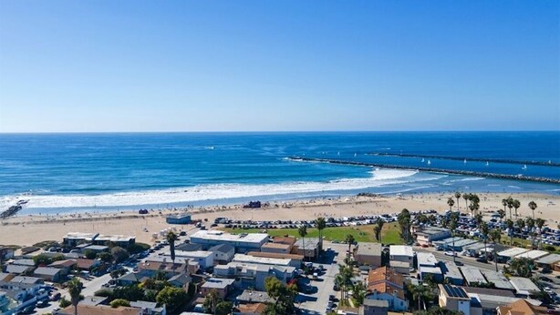 Uma vila costeira com uma praia, um cais e uma fileira de casas.