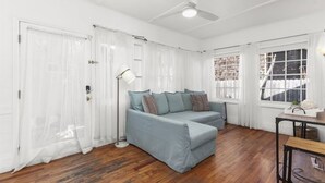 Quarto com sofá azul claro, luminária de chão e mesa com cesta.