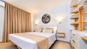 Een hotelkamer met een groot bed, een nachtkastje, een wandlamp en een houten dressoir.
