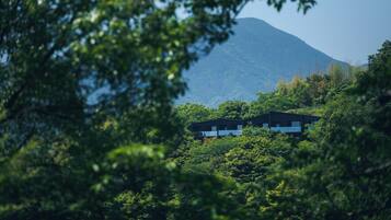 Un bâtiment moderne niché au milieu d’une végétation luxuriante, avec une montagne en toile de fond.