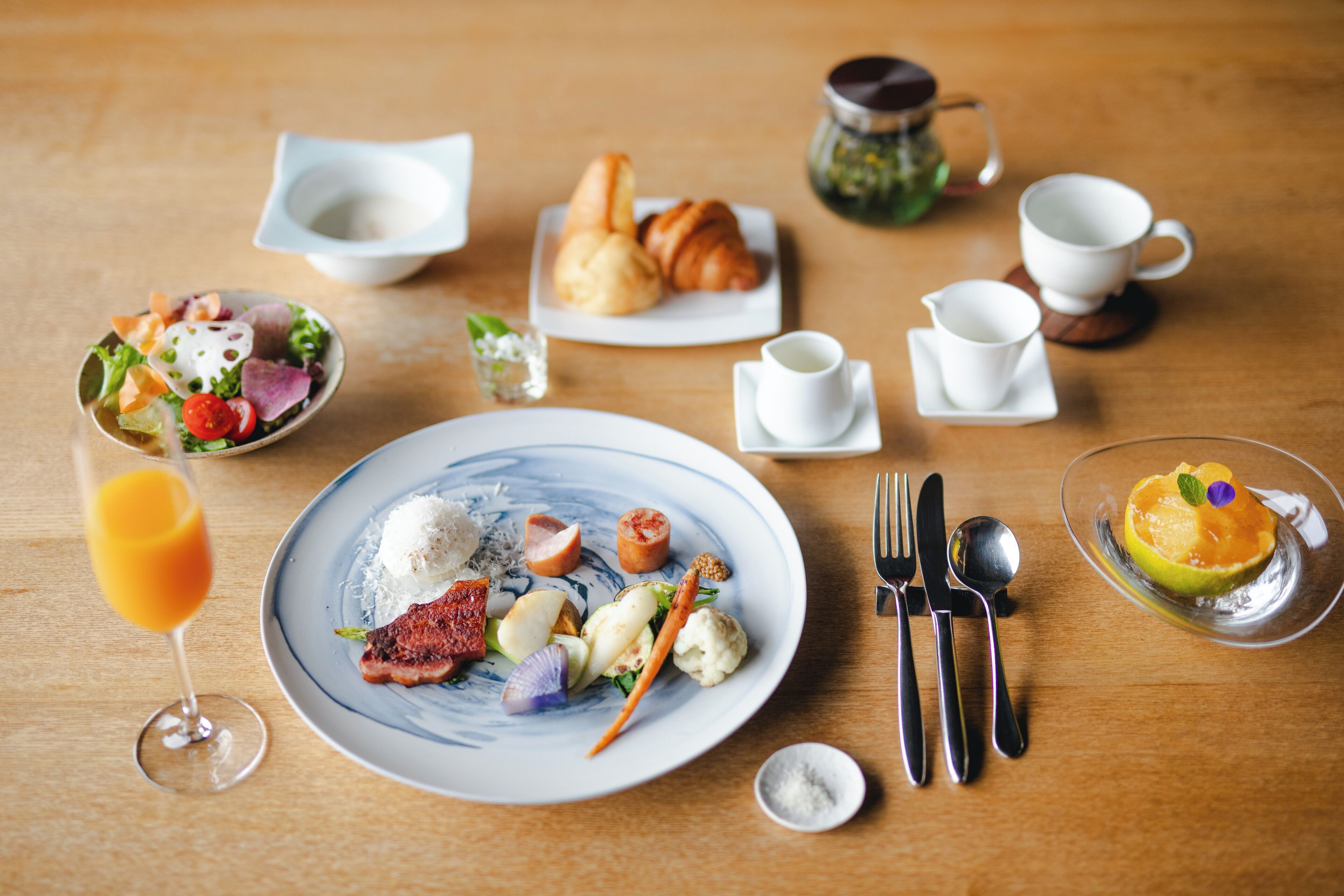 A breakfast setting with a plate of food, a glass of orange juice, and a croissant.