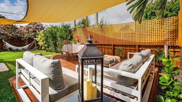 Une terrasse avec des meubles d’extérieur blancs, une lanterne et un hamac.