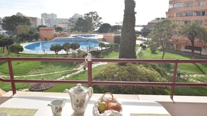 A balcony with a table set for breakfast, overlooking a swimming pool and a landscaped garden. - Apartment in Roses with pool, close to the beach and center, ideal for a comfortable and relaxing holiday. (Roses)