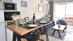 A dining area with a wooden table, black chairs, a vase with flowers, and a microwave above the counter.