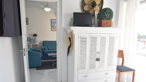 A room with a white cabinet, a television, and a potted plant.