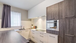 Eine moderne Küche mit einem dunklen Holzschrank, weißen Schubladen und einem Edelstahlbackofen.