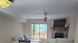 A dining area with a wooden table and chairs, a sofa, and a fireplace. - Tranquil 2-bedroom condo in Augusta with AC, WiFi (Augusta)