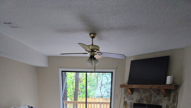 A living room with a white sofa, a ceiling fan, a fireplace, and a sliding glass door leading to a wooden deck. - Tranquil 2-bedroom condo in Augusta with AC, WiFi (Augusta)