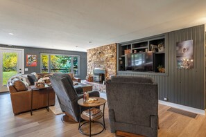 A modern living room with a stone fireplace, a flat-screen TV, and a cozy seating area.