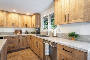 Une cuisine moderne avec des meubles en bois, des appareils électroménagers en acier inoxydable et une grande fenêtre qui laisse entrer la lumière naturelle.