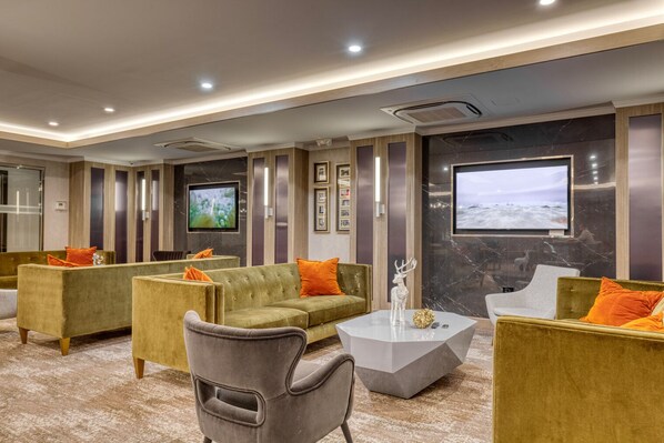 Relax in our spacious lobby, featuring plush sofas, a large flat-screen TV, and elegant artwork.