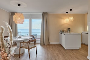 Une cuisine moderne avec un coin repas, une vue sur la mer et un balcon.