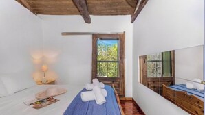 Ein Schlafzimmer mit Bett, Nachttisch, Lampe, Fenster und Spiegel.