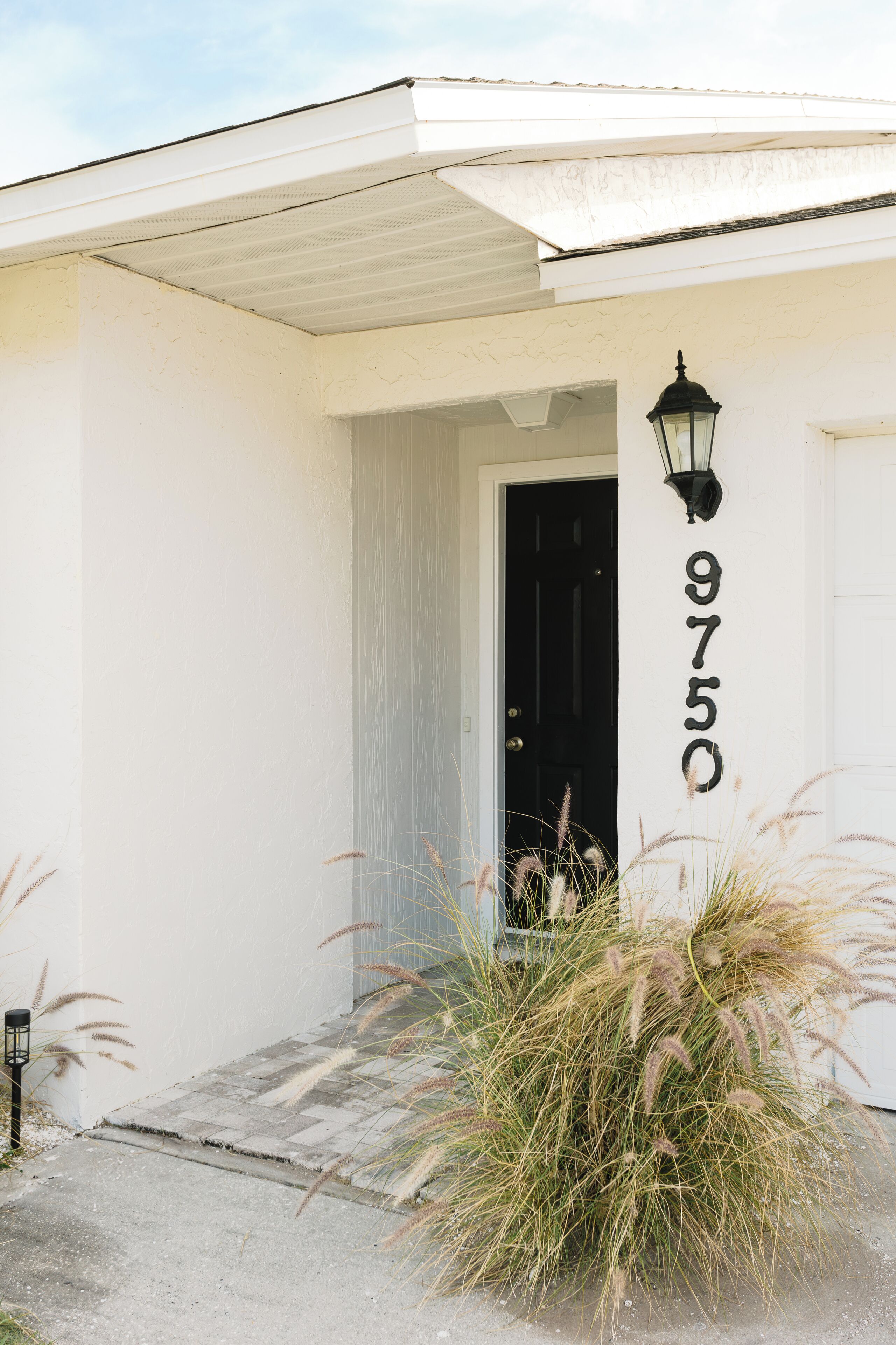 A white building with a black door and a number '9750' on the wall.