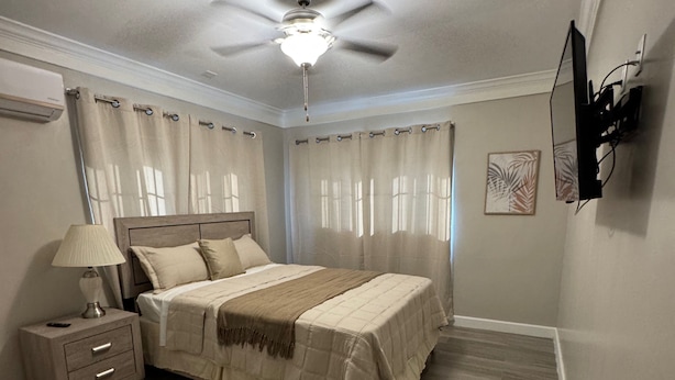 A bedroom with a bed, nightstand, lamp, and ceiling fan. - Nassau Escape: Beach and More (Nassau)
