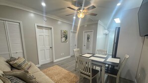 A dining area with a table and chairs, a ceiling fan, and a television mounted on the wall. - Nassau Escape: Beach and More (Nassau)