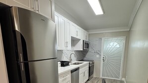 A modern kitchen with white cabinets, stainless steel appliances, and a wooden dining table. - Nassau Escape: Beach and More (Nassau)