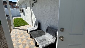 A covered patio area with a seating arrangement, a door, and a white exterior wall. - Nassau Escape: Beach and More (Nassau)