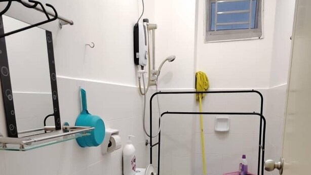 A compact bathroom with a sink, toilet, and shower. There is a window above the shower, and a towel rack with a yellow towel. - Tebrau City Residence by Natol (Johor Bahru)