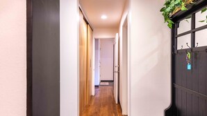 A narrow hallway with wooden flooring, white walls, and a black door with hooks. - Elkhorn Retreat: Condo with Pond Views, Pool & Pet-Friendly (Sun Valley)