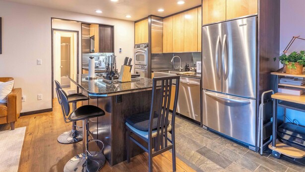 A modern kitchen with stainless steel appliances, a central island with bar stools, and wooden cabinetry. - Elkhorn Retreat: Condo with Pond Views, Pool & Pet-Friendly (Sun Valley)