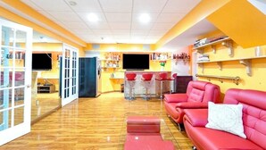 Una habitación con sofá rojo, una mesita y una zona de bar con taburetes.