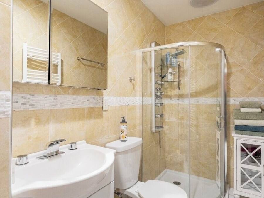 Un baño moderno con ducha envuelta en vidrio, un lavabo blanco y un inodoro.