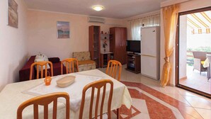 Angolo pranzo con tavolo imbandito per quattro persone, divano e televisione sullo sfondo.