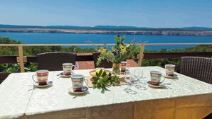 Un tavolo apparecchiato con tazze da caffè e un vaso di fiori, con vista panoramica su un lago e montagne.