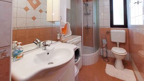 Un bagno con lavandino, WC, doccia e uno specchio.