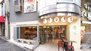 Un ristorante con un cartello che indica 'HOURS' e una lavagna con il menu all'esterno.