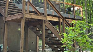 A wooden cabin with a glass-enclosed upper level and a staircase leading to it.