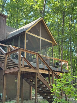 A wooden cabin with a glass-enclosed upper level and a staircase leading to it. - 5BR chalet w/ BBQ grill & deck (Berkeley Springs)