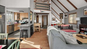 A spacious loft-style living area with a kitchen, dining space, and a staircase leading to an upper level.