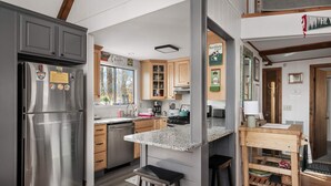 A modern kitchen with stainless steel appliances, wooden cabinets, and a granite countertop.