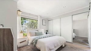 Un dormitorio con cama, ventana, armario y espejo.